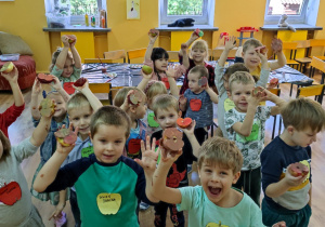 Przedszkolaki uśmiechają się do zdjęcia z pomalowanymi jabłkami